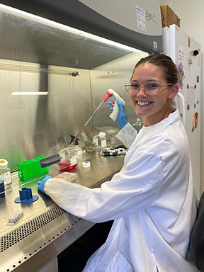 A student in a white lab coat is working in a research laboratory.