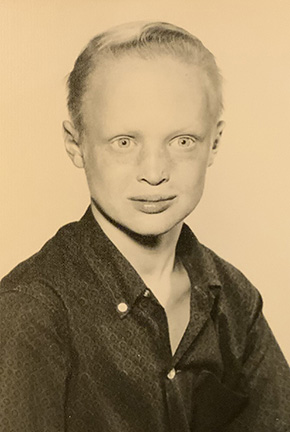 This is a school picture of John in sepia. he's wearing a dark, button down shirt.