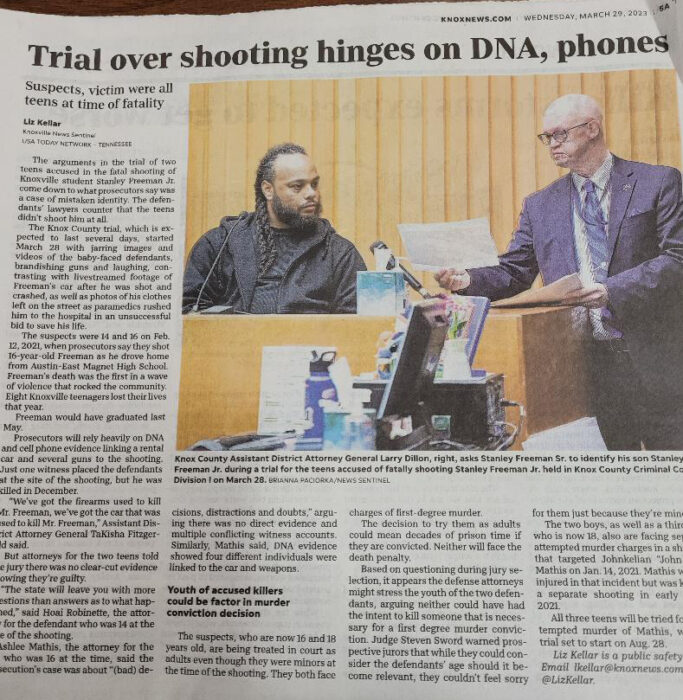 This is a newspaper article about a trial. In the photo, it's a courtroom with two men. Lawrence, the attorney, is in a suit and showing a piece of paper to a man on the stand.