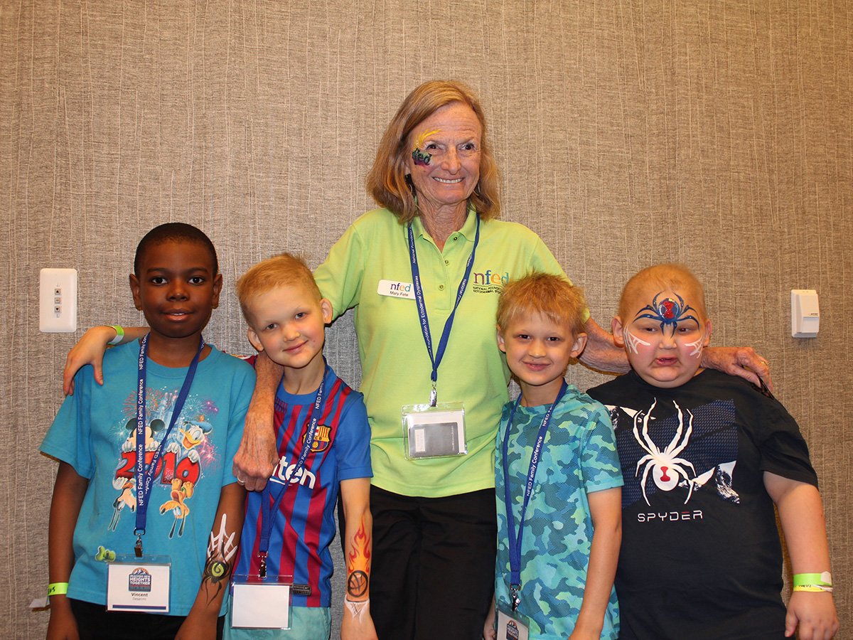 Mary Fete stands with her arms around four boys affected by ectodermal dysplasia. She invites families to attend the Stand Together Conference.