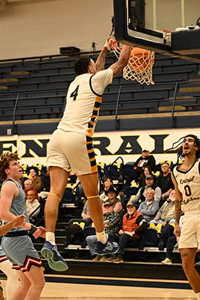 Jacobi slam dunks a basketball in a game while other players and the crowd watches.