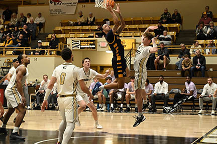 Jacobi shoots a basektball as other players look on.