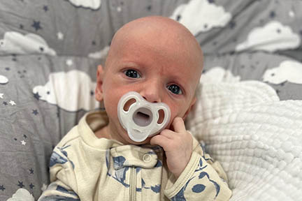 Baby Matthew when he's a few months old and sucking a pacifier.