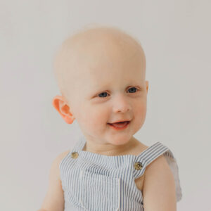 This is a head shot of baby Jack at one year old. He's wearing bib overalls.
