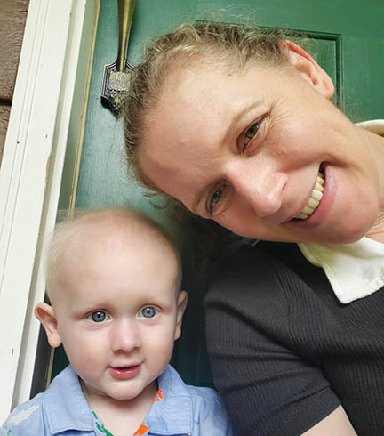 Elizabeth and baby Jack are sitting outside the door of a house.