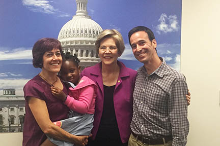 Four people stand in front of a photo of the U.S. Capitol.