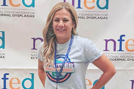 Lindsey stands in front of a backdrop that has the NFED logo repeated on it.