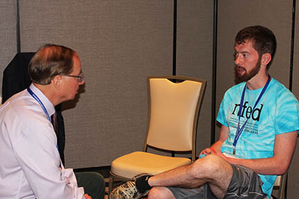 Dr. Stanford sits across from a young man affected by EEC syndrome in a hotel conference room.