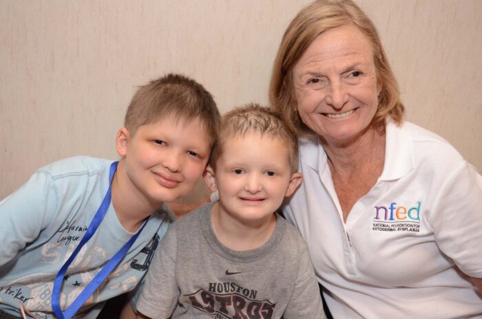 Mary poses with two boys who have sparse hair due to ectodermal dysplasia.