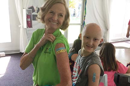 Mary and a child with AEC syndrome show their left arm where each have a band aid from having a skin biopsy done.