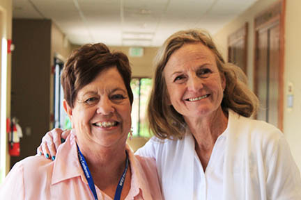 Mary has her arm around Mary Fete. They are standing in a hotel hallway.
