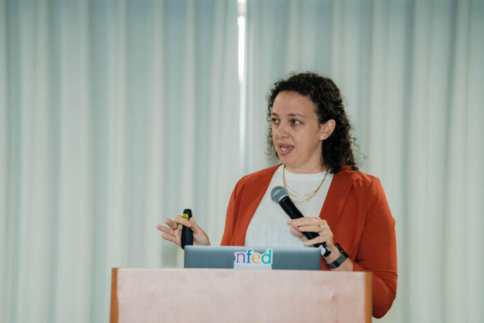 A doctor presents information about ectodermal dysplasia as she stands behind a podium with a microphone in her hand. There's a laptop on the podium.