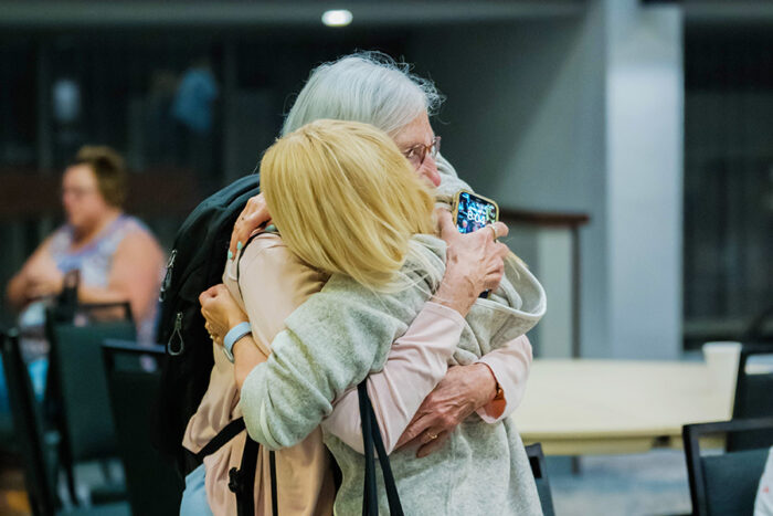 Two women are hugging each other/