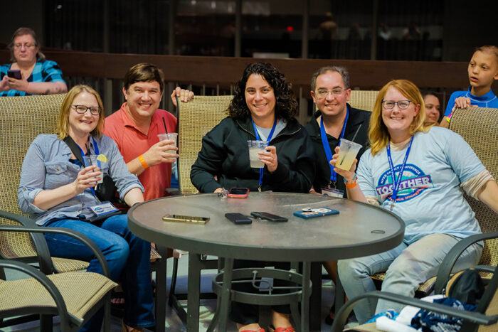 Five men and women are sitting pool side and enjoying a beverage at the Family Conference 