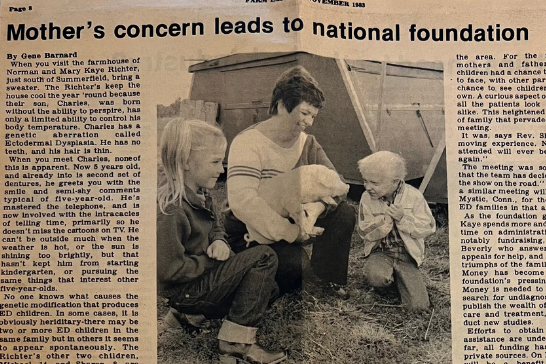 This is an image of a newspaper article from 1983. Title reads, Mother's concern leads to national foundation. The photo shows a  mom, Mary K. Richter, holding a pig with a piece of farm equipment behind her. Her young daughter and son kneel by her. The son has x-linked hypohidrotic ectodermal dysplasia. 