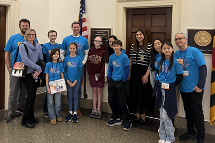 Numerous NFED advocates pose outside a Congressional office. Most are wearing a teal ELSA t-shirt.
