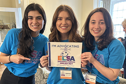 Three young women wearing teal ELSA shirts hold a sign saying, "I'm advocating for ELSA."