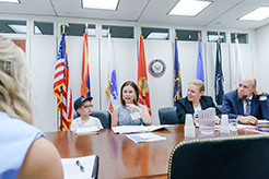 Four advocates sit at a conference table across from a legislative aid. A woman is telling her son's story with ectodermal dysplasia.