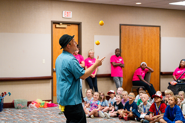 A juggler is entertaining a group of children.