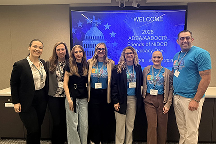 Seven ELSA advocates post in front of a screen that says "Welcome. 2026 AADOCR/ADEA/FNIDCR Hill Day."