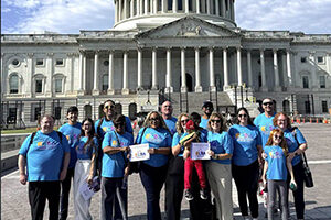 A group of ELSA advocates in teal ELSA shirts pose in front of the U.S. Capitol building.