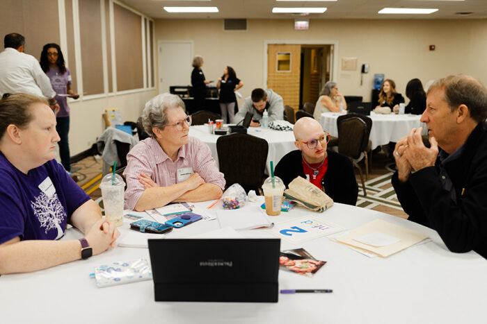 A man is explaining something to a mom, grandma and teenager.
